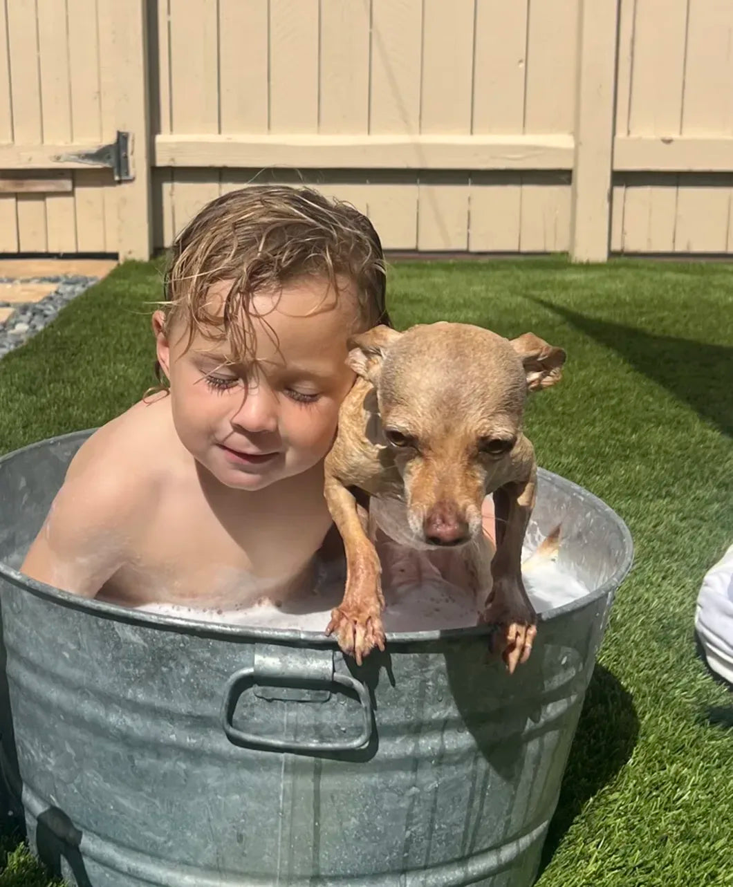 A child and dog sharing a bath outside
